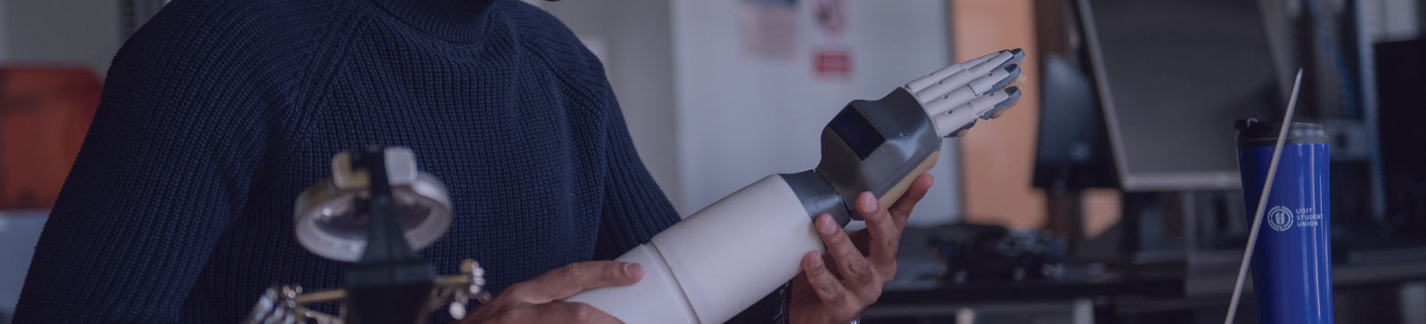 Close up of a student holding a robotic arm.