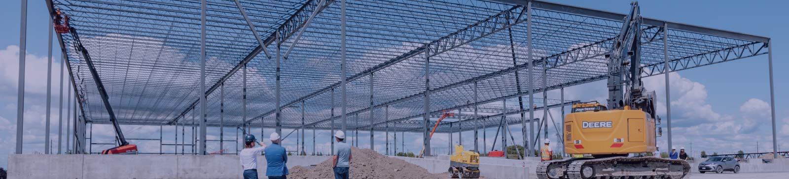 Construction workers and equipment alongside the frame of a commercial building.