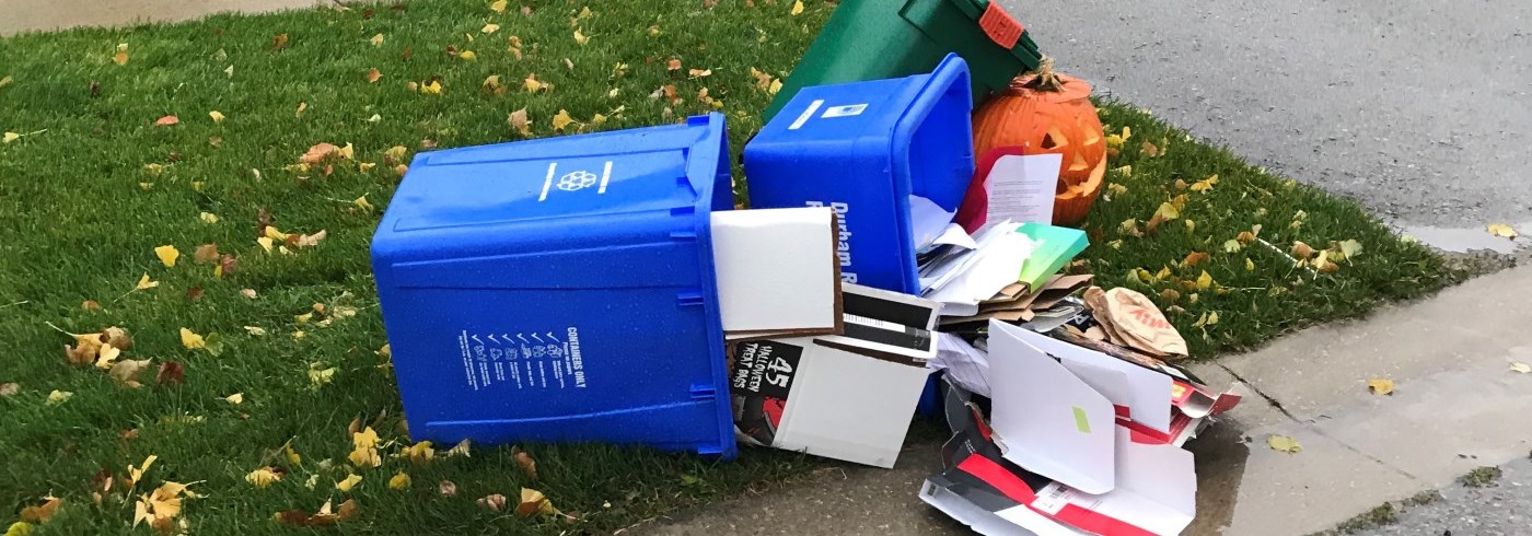 Blue box recycling materials tipped over on a windy day