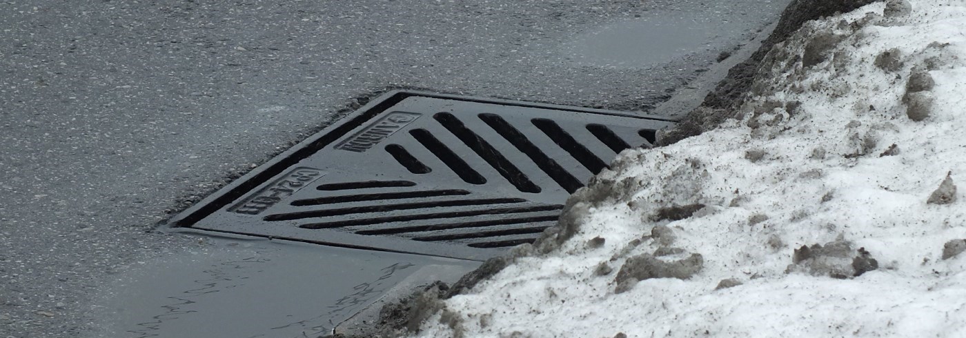 Storm sewer at side of road in winter