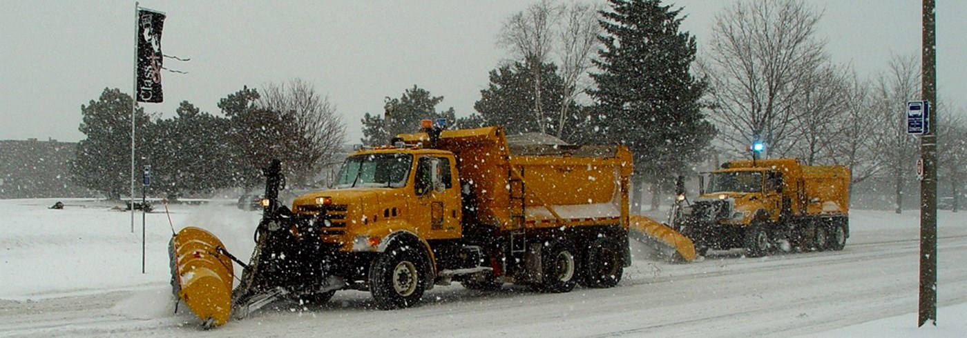 Two yellow Region of Durham snow plows clearing snow off of a road