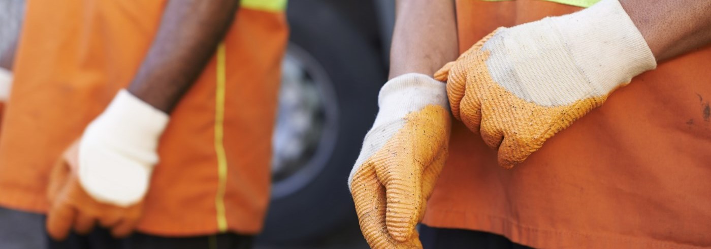 Two men wearing orange construction shirts and gloves