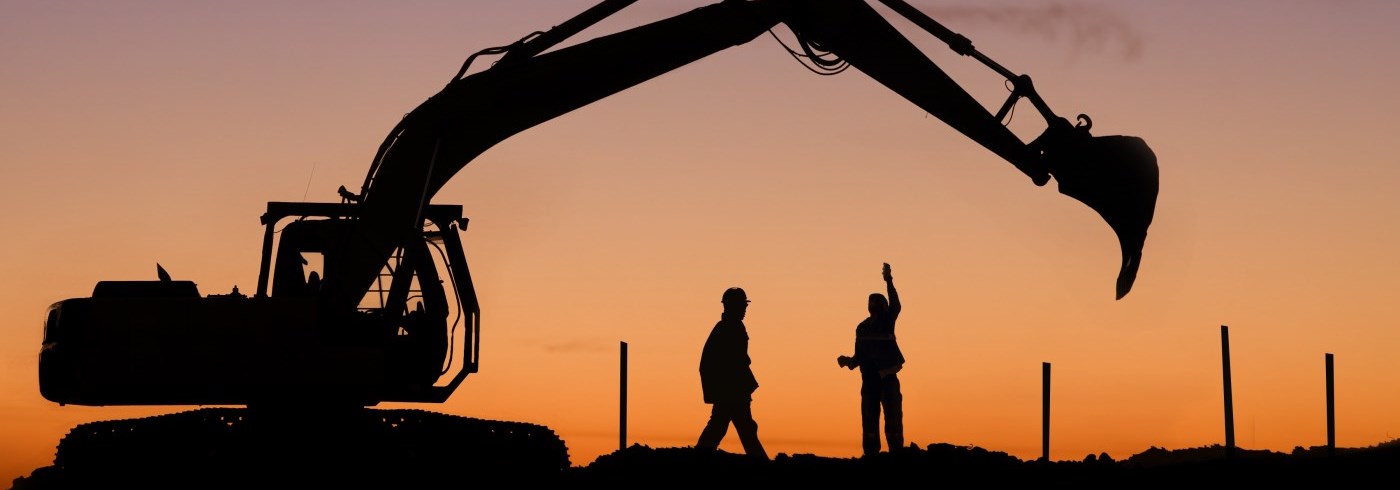 Two workers with machinery at sunset