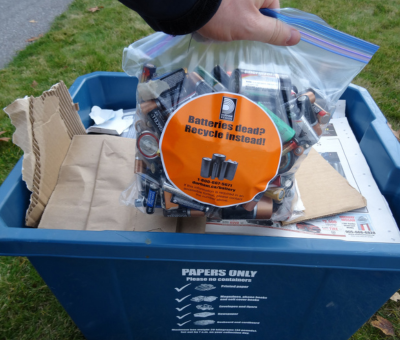 A person putting a bag of batteries into a Blue Box