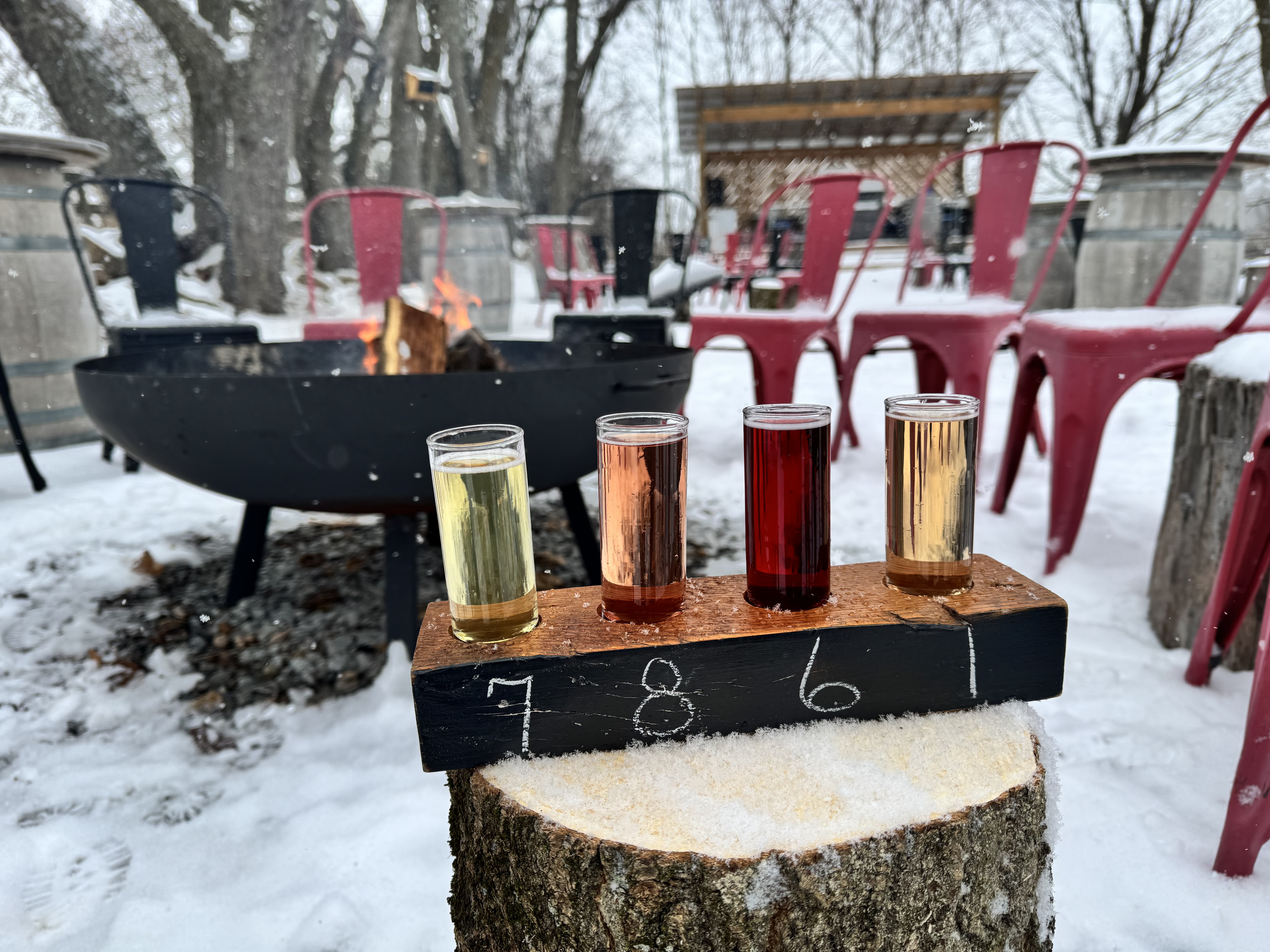 Flight of cider in front of an outdoor firepit on a winter day at Banjo Cider in Uxbridge, Ontario