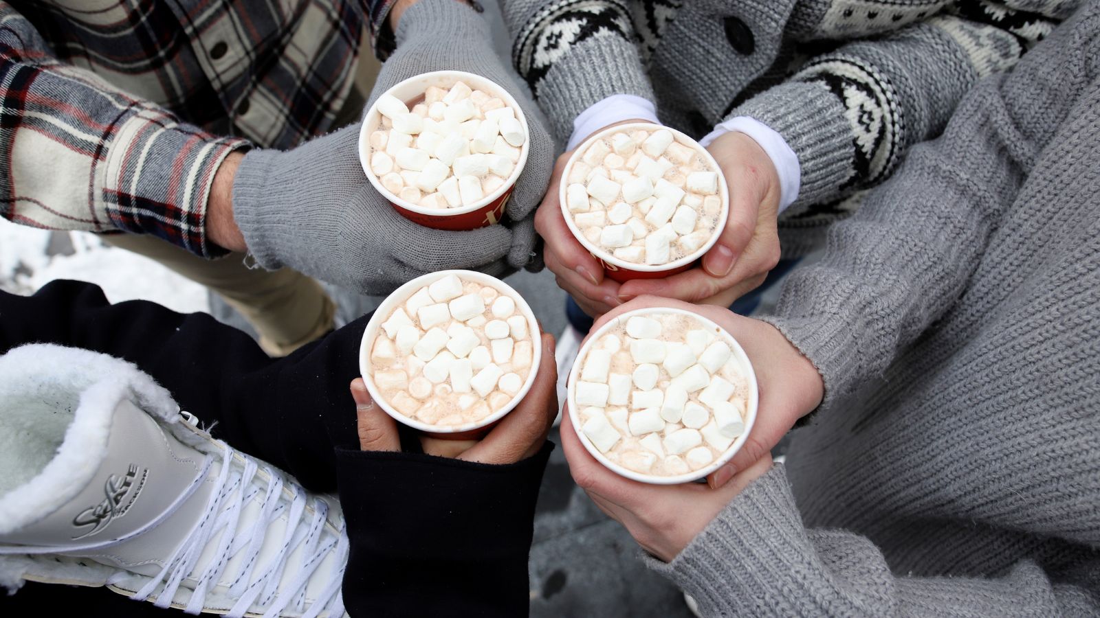 Image of four people cheersing their hot chocolates topped with marshmallows