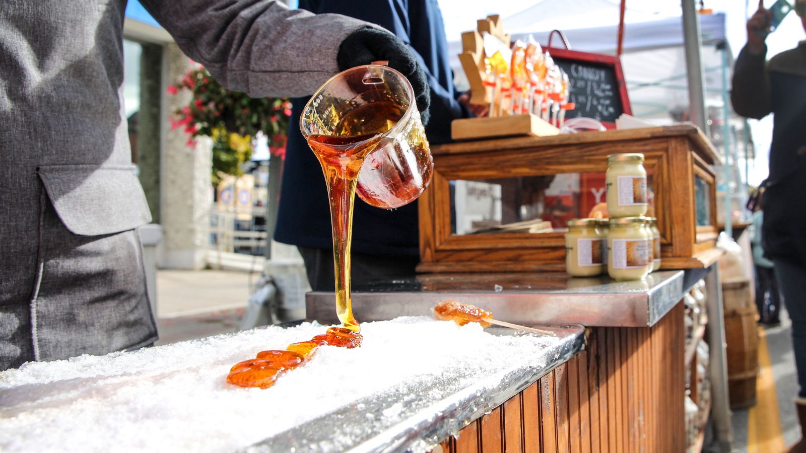 Image of a person pouring maple syrup onto snow to make taffy at a festivall