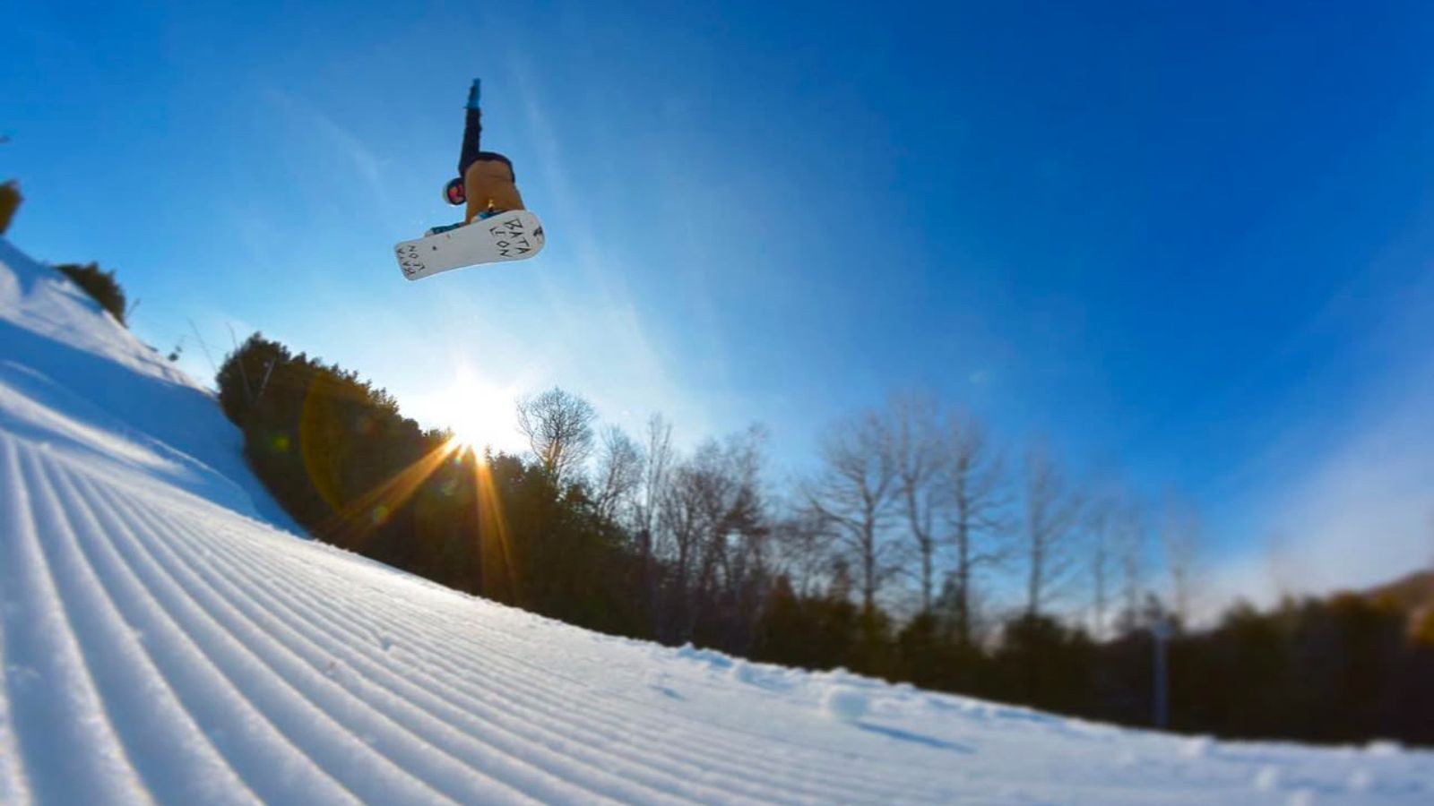 Image of a snowboarder in the air after going off a jump with a beautiful blue sky behind them