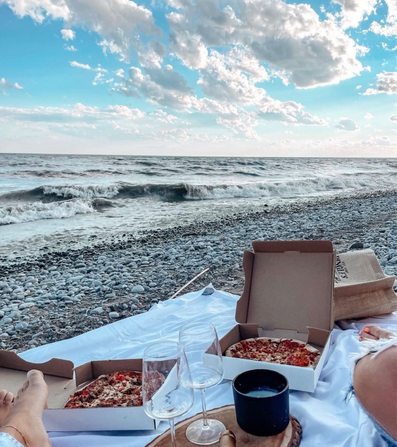 Image of two pizza boxes on a picnic blanket on the beach