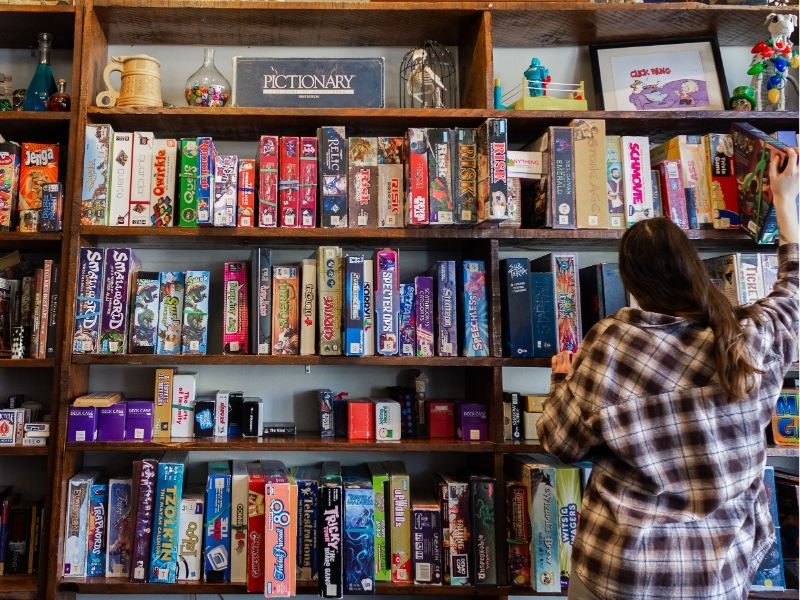 Image of a person standing in front of a wall covered in shelves of board games