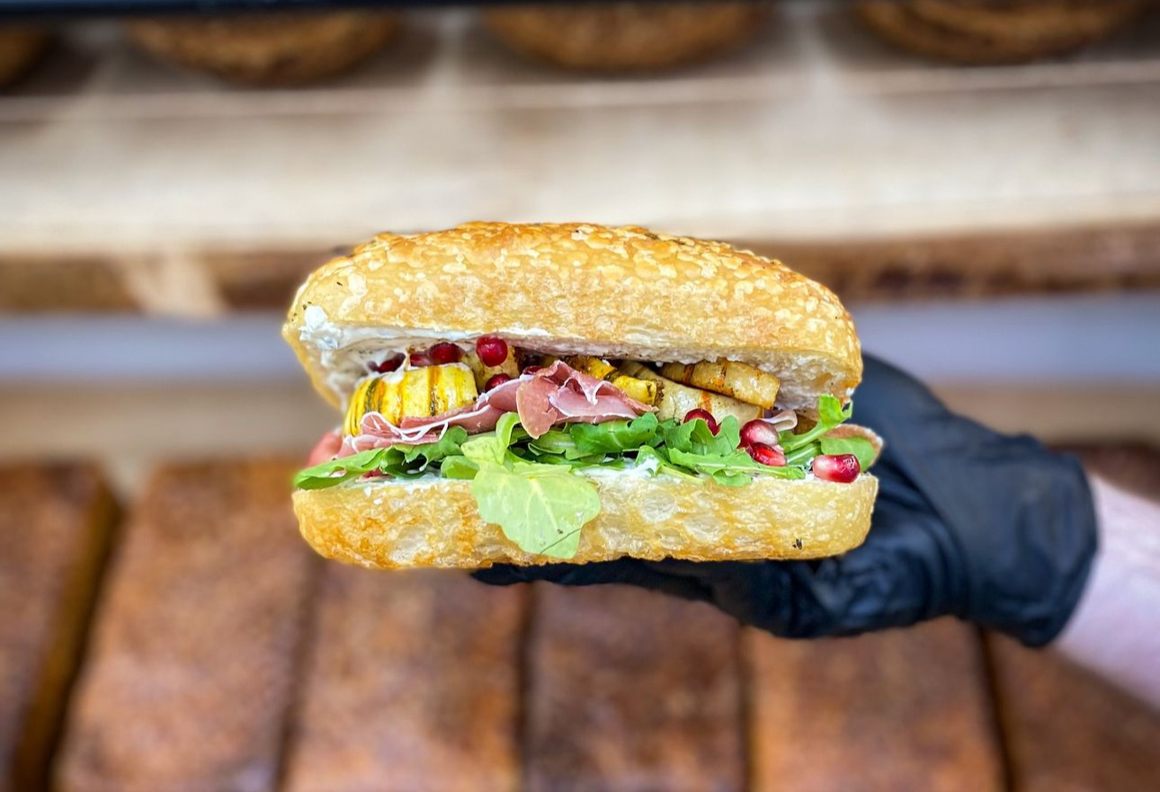 Image of a massive sandwich made on focaccia being held up by a hand