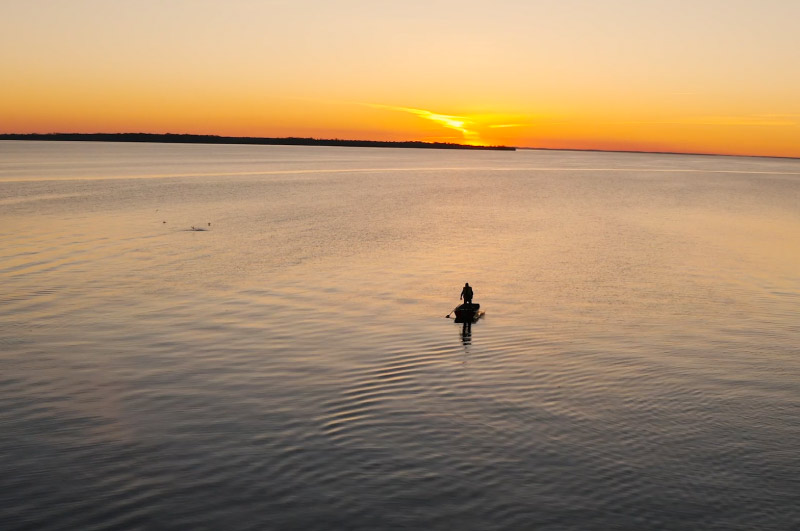 Someone in a boat on Lake Simcoe at sunset.