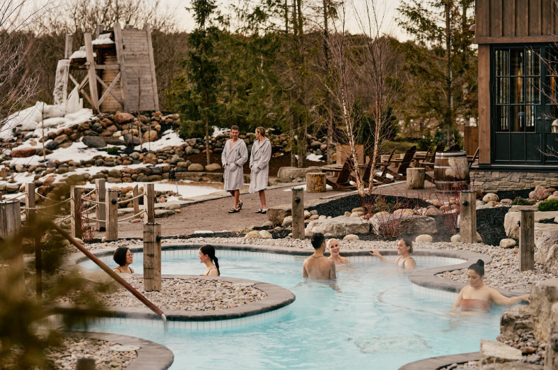 People relaxing in hot pools and walking around Thermea Spa in the winter.