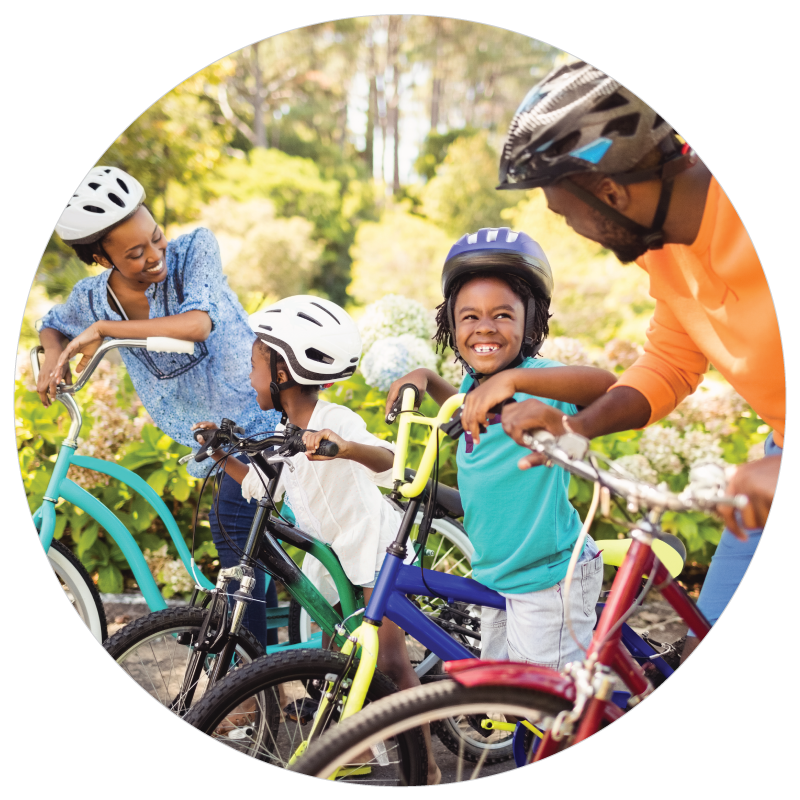 Family cycling next to a forest.