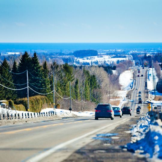 Vehicles driving down a hill in the winter in Durham Region, Ontario