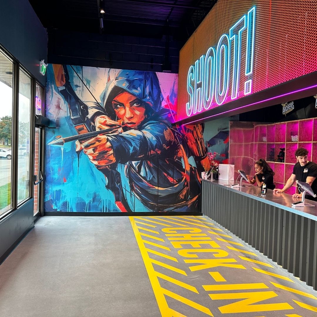 Image of the front lobby of an indoor archery venue with neon lights and a colourful mural