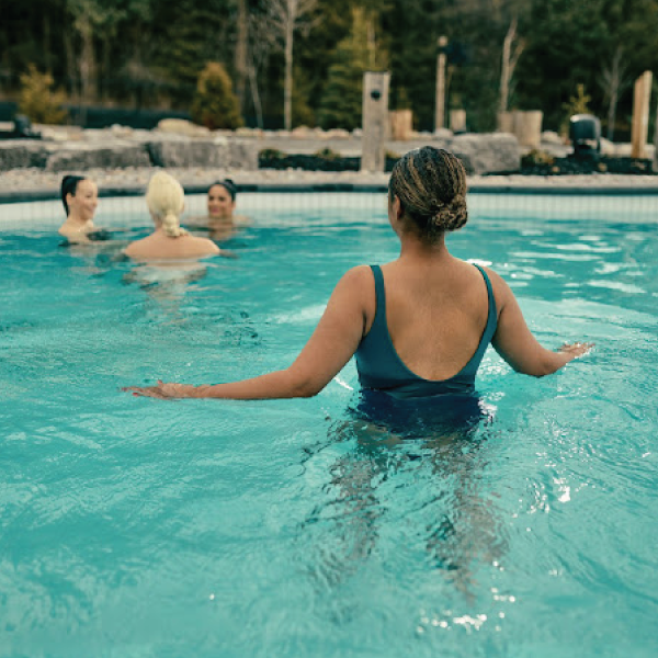 Woman at Thermea Spa in a pool with calm water with trees in the background.