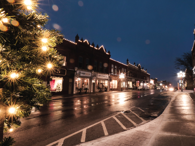 Downtown Port Perry storefronts at night with Christmas lights.