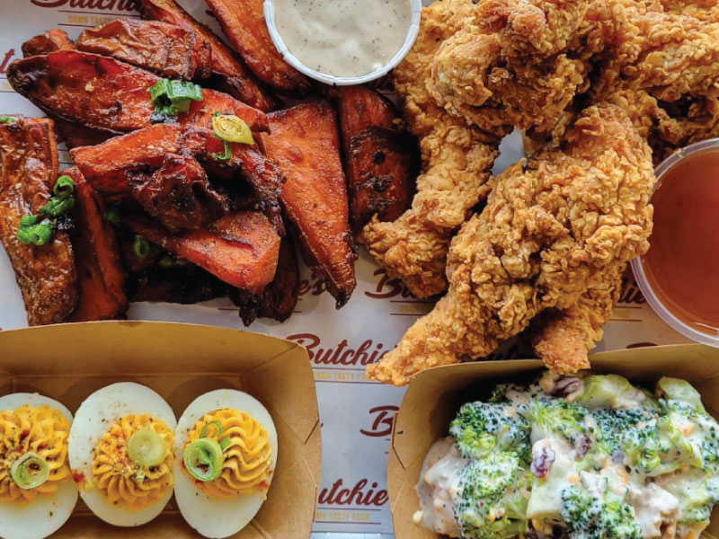 Close up of fried chicken, sweet potato wedges, broccoli salad, and devilled eggs from Butchie's.