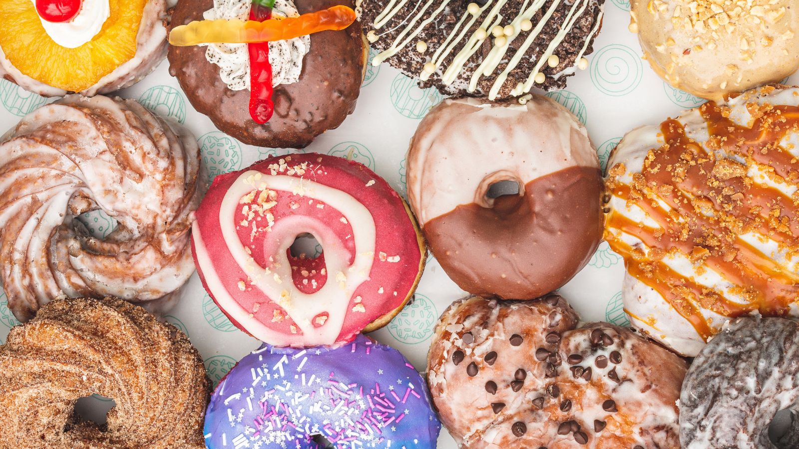 Aerial image of a dozen gourmet doughnuts.