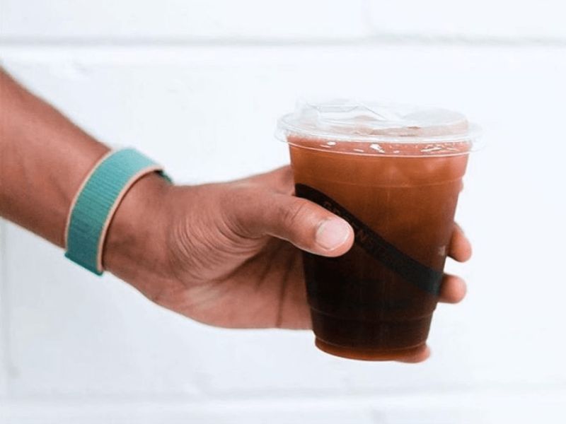 Image of a hand holding an iced coffee in a clear to-go cup