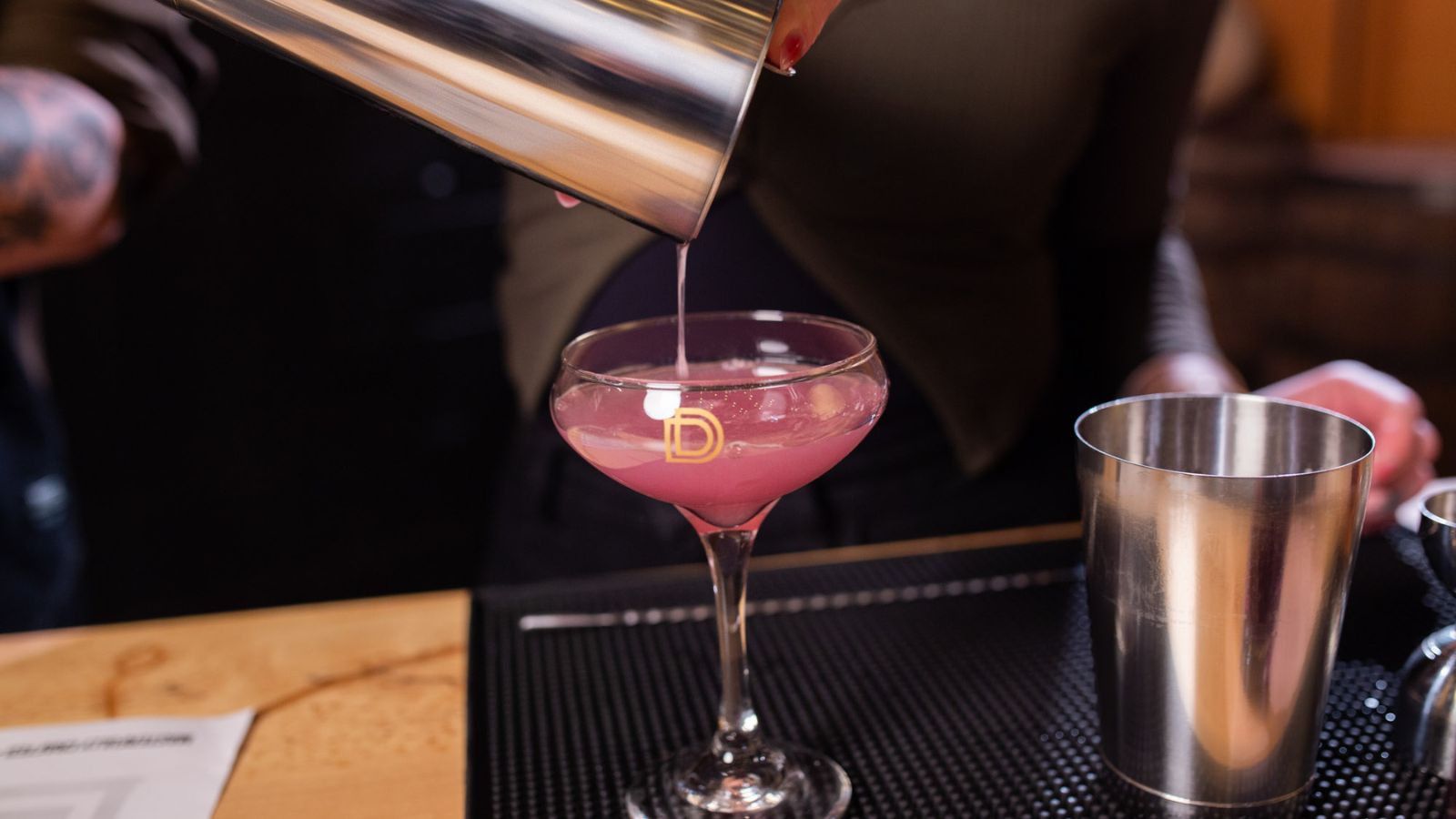 Image of a cocktail being poured from a cocktail shaker into a coupe