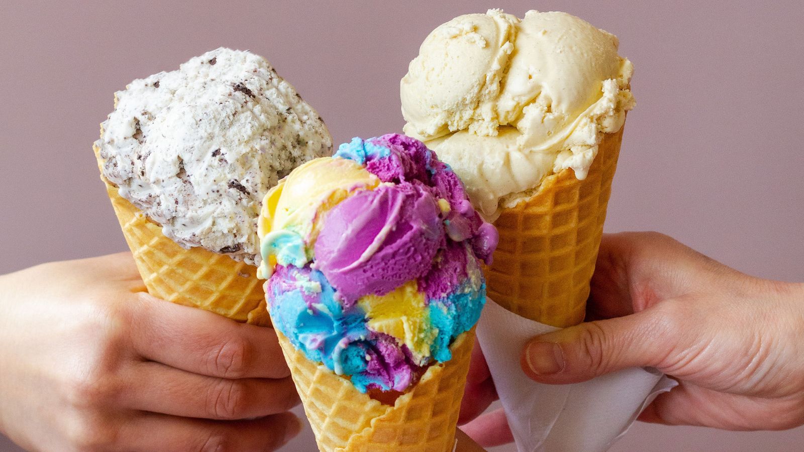 Image of three people doing a "cheers" with ice cream cones of all different flavours