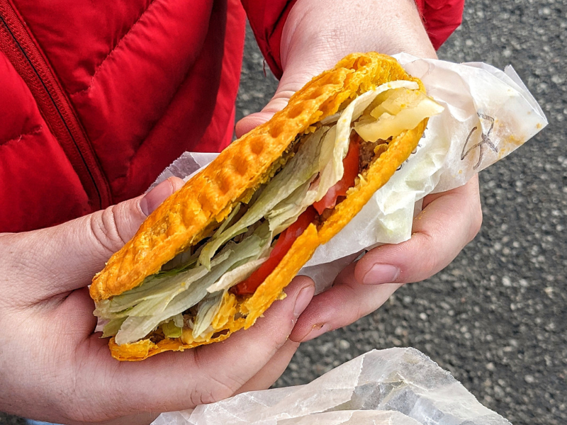 Image of a Jamaican patty stuffed with lettuce, tomato, and cheese 