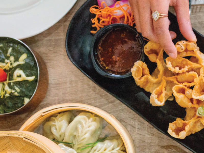 Overhead shot of a hand grabbing food on a table with shared plates.