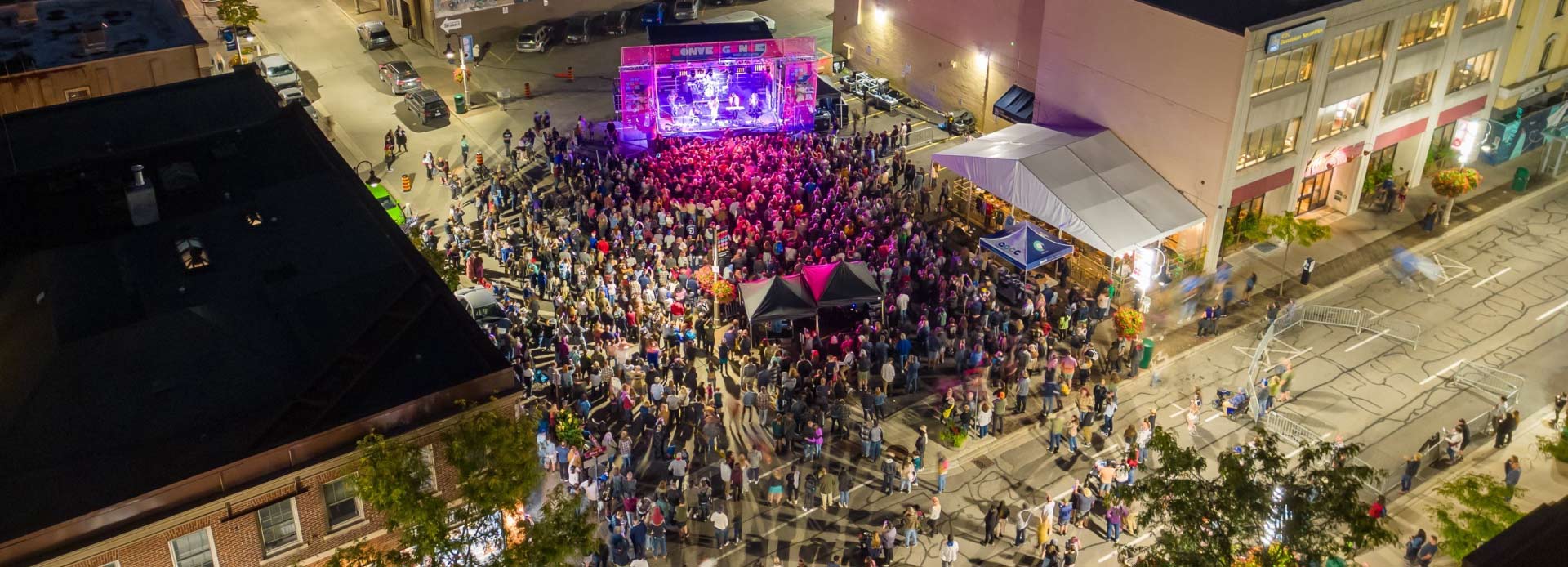 Aerial view of a large crowd watching a band on stage outdoors at Convergence Art and Music Festival.