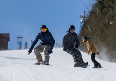 Two snowboarders making their way down a hill on a blue sky day