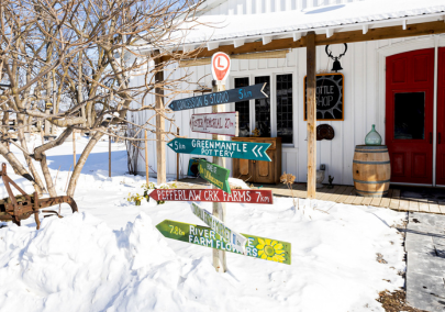 A sign post in front of a cidery with signs pointing to stops on a trail of rural businesses