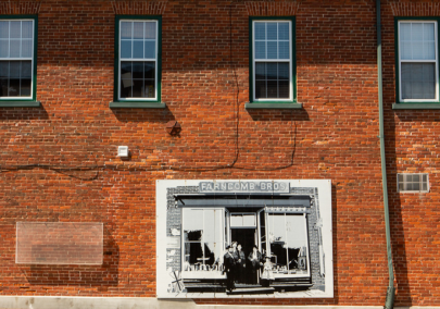 Image of an exterior red brick wall with a small mural of an old image 