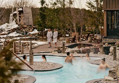 Image of a guests in robes walking through a Nordic spa and enjoying the hot pools